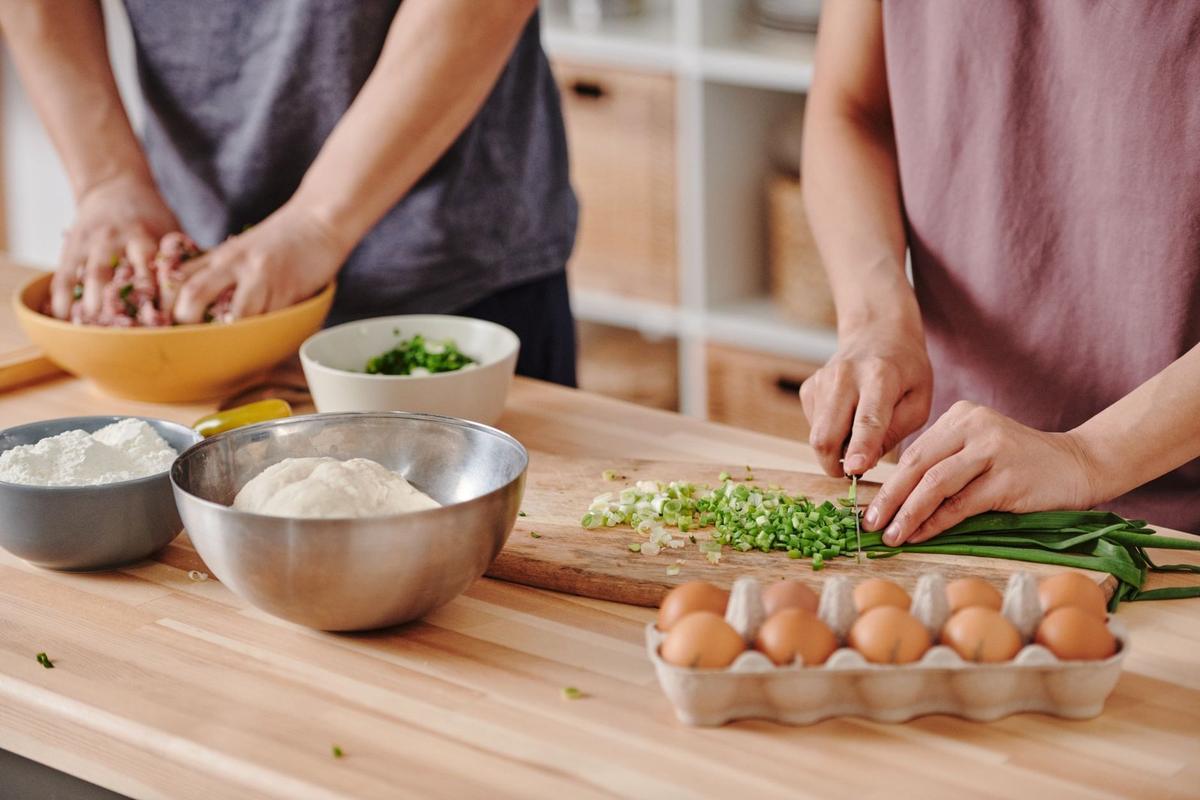 Deux mains cuisinent sur une table en bois avec des ingrédients et des ustensiles Deux mains cuisinent sur une table en bois avec des ingrédients et des ustensiles